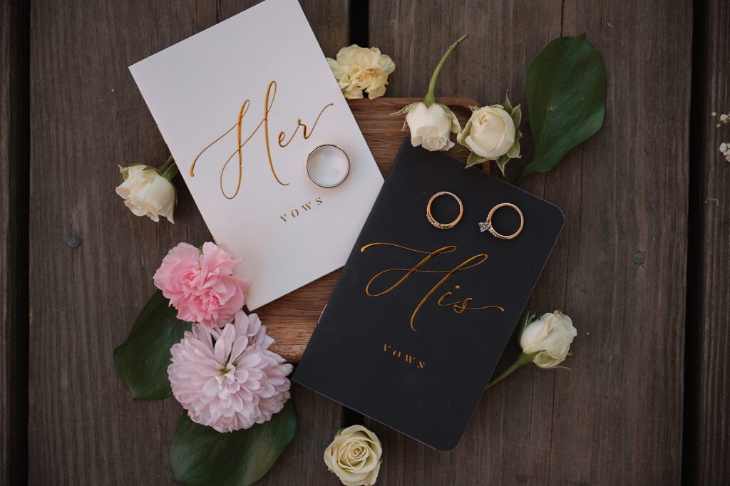 Wedding rings and vow books laid out with flowers