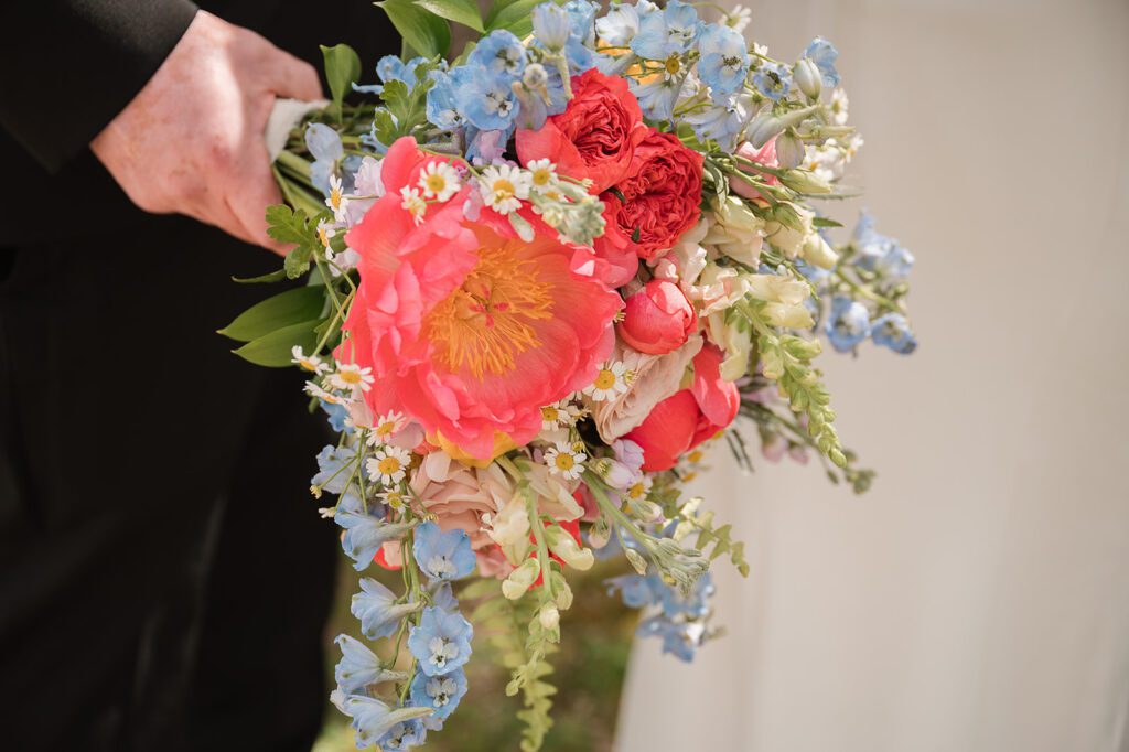 A bridal bouquet of coral and blue blooms