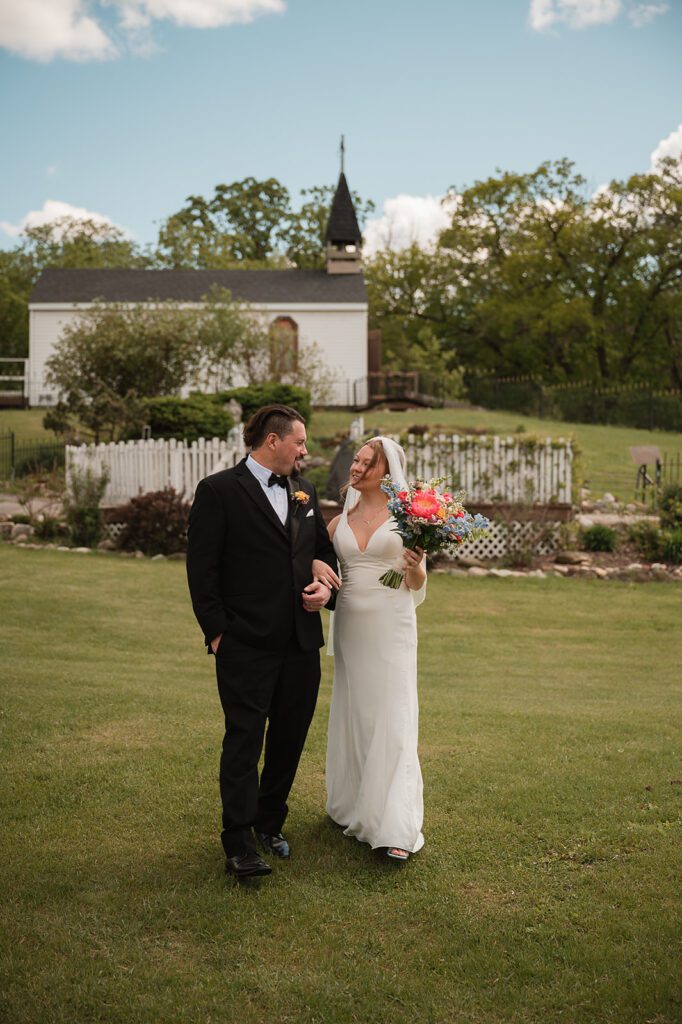 A bride and groom on the lawn with St. Rose Chapel behind them