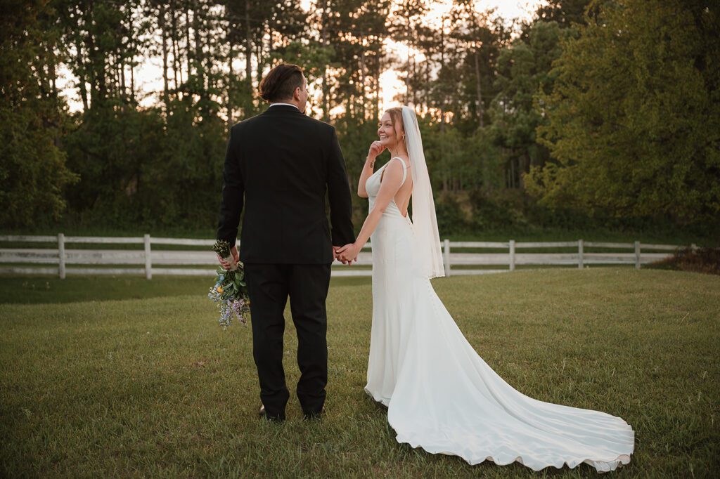 A bride and groom walking away, her veil trailing behind