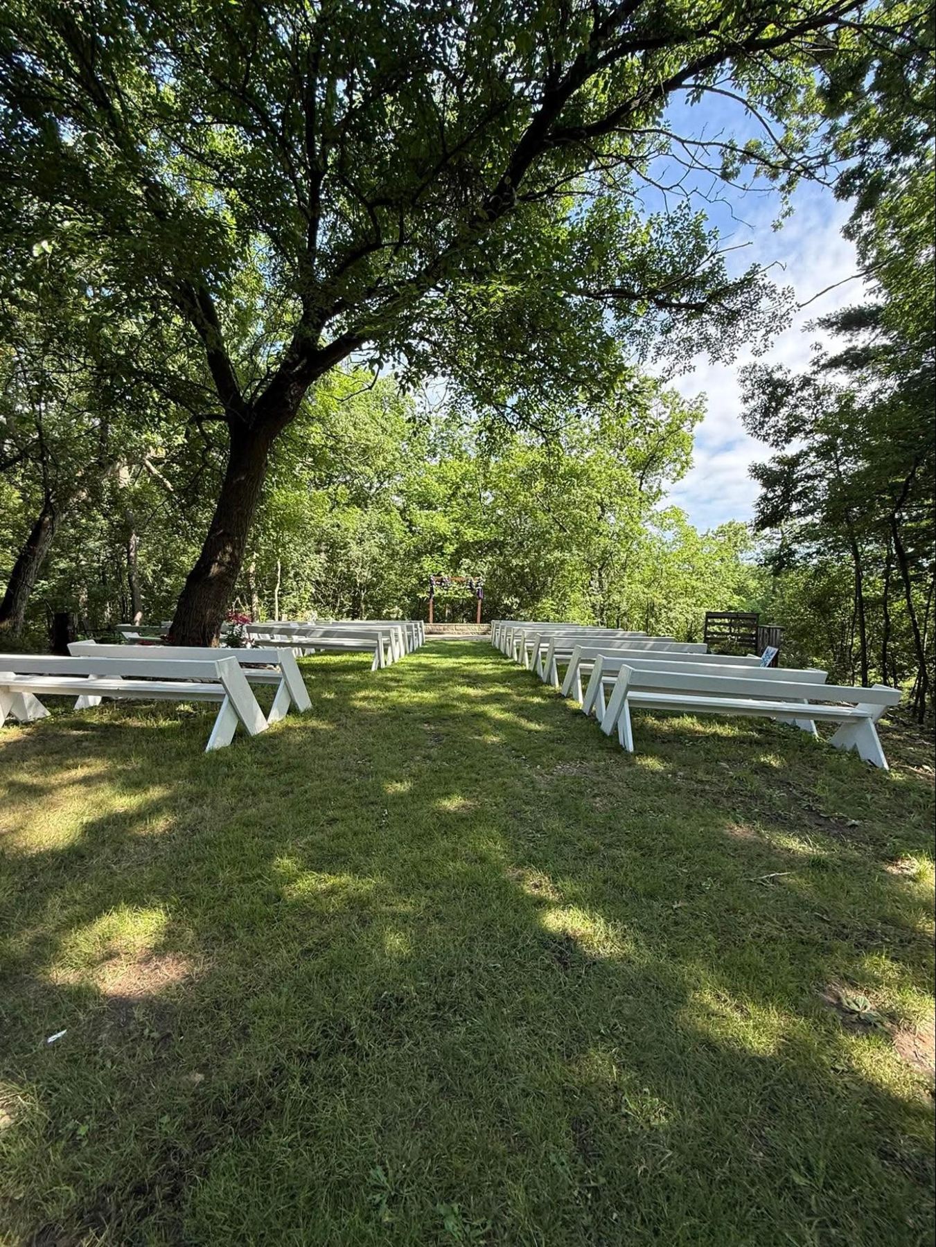 Wooded ceremony site with white benches