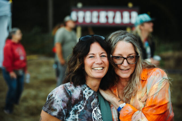Two friends hugging by the Stockyard stage sign